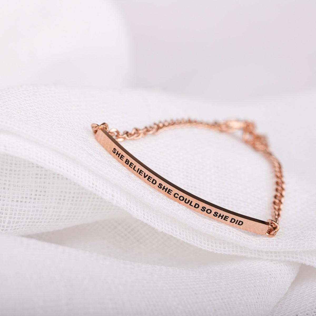 Close-up of She Believed She Could So She Did chain bracelet showing engraved message